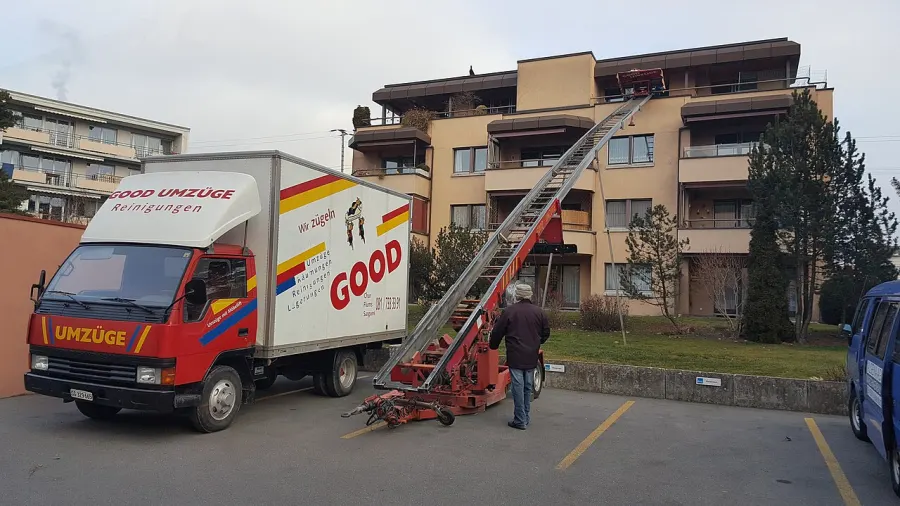 Camion de déménagement et monte-meuble déployé contre une façade